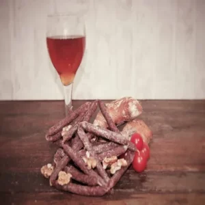 sauciflettes aux noix présentées avec pain, tomates et vin sur planche rustique
