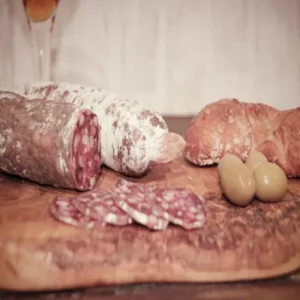 Saucisson au cerf posé sur une planche avec olives et pain