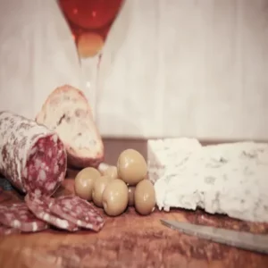 Saucisson au roquefort avec pain, olives et tranche de fromage sur planche en bois