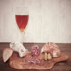 Saucisson à l’autruche tranché avec pain, olives et verre de bière ambrée sur planche rustique