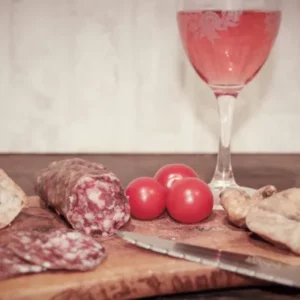 saucisson aux figues de la Salaison Montserret accompagné de pain, figues séchées et tomates cerises sur planche en bois