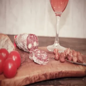 Tranches de saucisson aux noisettes sur planche avec tomates, noisettes et pain