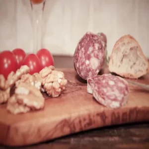 saucisson aux noix tranché avec pain, tomates et noix sur une planche en bois