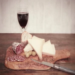 saucisson au Beaufort tranché avec olives, fromage, pain et vin rouge sur planche rustique