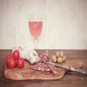 Saucisson nature tranché sur planche en bois avec olives vertes et tomates – produit Montserret