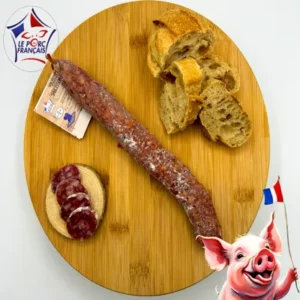Saucisson piment Espelette artisanal, tranché sur planche ronde en bois clair, avec pain rustique et étiquette Le Porc Français – Salaison du Velay